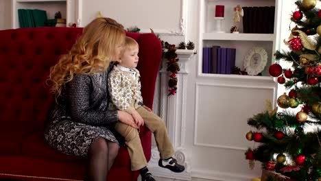 Mom-and-son-sit-on-the-couch-near-Christmas-tree.