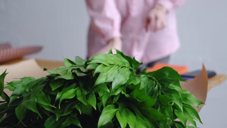 Florist-prepares-tools-to-create-a-beautiful-bouquet.-Against-the-background-of-greenery.