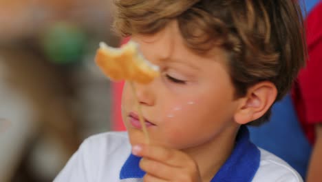 Niño-comiendo-galleta-en-una-fiesta-de-niños.-Muchacho-joven-con-la-mitad-come-galleta-masticando-azúcar-en-4K