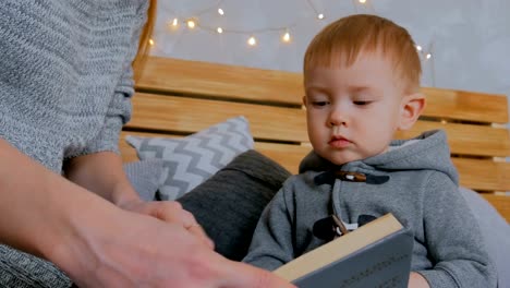 Young-mother-and-her-baby-son-reading-book-at-home