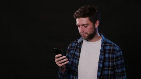 A-Man-Using-a-Phone-Against-a-Black-Background