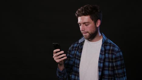 A-Man-Using-a-Phone-Against-a-Black-Background