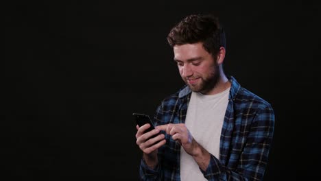 A-Man-Using-a-Phone-Against-a-Black-Background