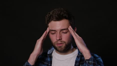 A-Man-Immitating-Headache-Against-a-Black-Background