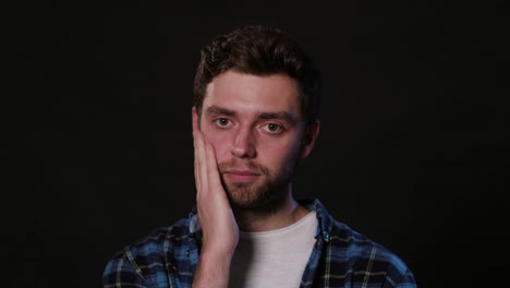 A-Man-Immitating-Toothache-Against-a-Black-Background