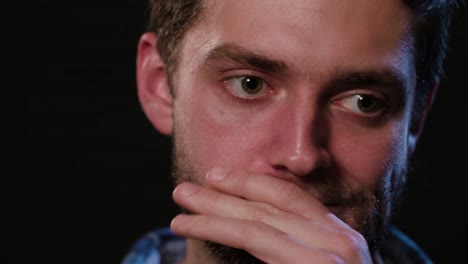 A-Man-Touching-his-Lips-Against-a-Black-Background