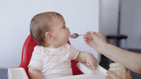 Porträt-für-ein-süßes-Kind,-wer-Babynahrung-aus-einem-Löffel-gefüttert-ist,-Mutter-füttert-ihr-Sohn-mit-leckerem-Essen