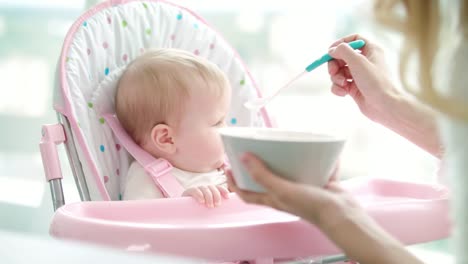 Mutter-Fütterung-Kind-mit-Babynahrung.-Kleinkind-Mädchen-essen-pürierte-Nahrung