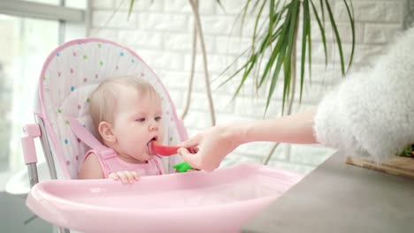 Little-baby-tasting-red-pepper.-Mother-feeding-baby-healthy-food