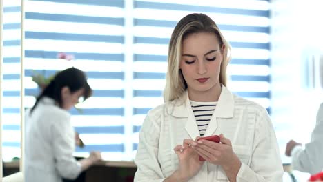 Ziemlich-Krankenschwester-mit-mobilen,-während-eine-andere-Krankenschwester-Reinigung-Rezeption