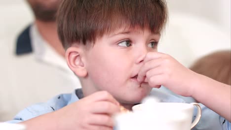 Concentrated-dark-hair-boy-eating-chocolate-croissant