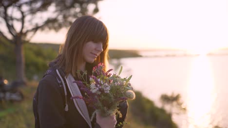 beautiful-young-woman-with-a-bouquet-of-wildflowers-on-the-coast-at-sunset