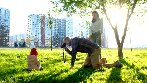 Young-father-takes-a-picture-of-a-young-daughter-in-a-park-at-sunset.-Happy-family-takes-pictures-of-a-child-in-nature