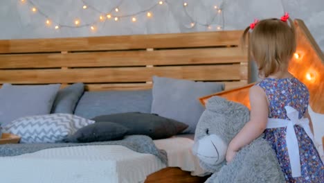 Portrait-of-funny-little-girl-with-bear-doll-at-home