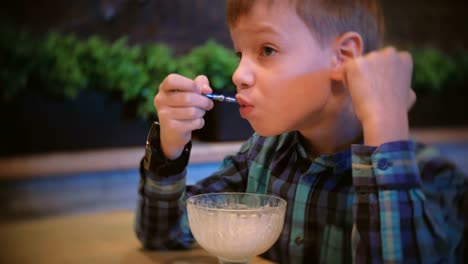 Boy-eats-ice-cream-and-watches-TV.-Side-view.