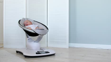 Sweet-newborn-baby-girl-sleeping-in-a-bouncer-chair-in-a-white-room