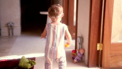 Happy-little-girl-with-toys-running-around-home