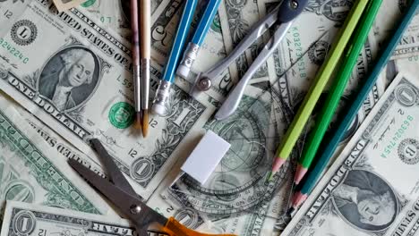 high-school-expenses,-concept,-pencils-on-money,-dollars,-rotating,-turning,-from-above