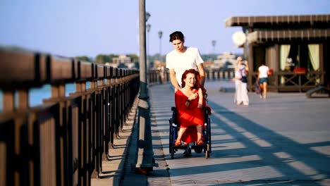 Rodillos-chico-A-discapacitados-a-una-niña-sonriente-con-el-pelo-rojo-en-una-silla-de-ruedas-en-el-paseo-marítimo