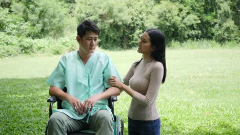 Hombre-joven-discapacitado-en-silla-de-ruedas-con-su-alegría-de-la-novia-en-el-parque-junto