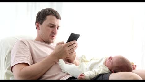 Relaxing-man-using-phone-with-baby-on-knees