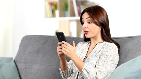 Mujer-sorprendida-leyendo-el-contenido-del-teléfono-en-casa