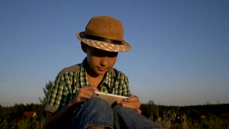 junge-Einsatz-Tablet-im-Feld-bei-Sonnenuntergang,-im-Freien-sitzen