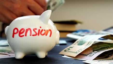 Pension-written-on-a-piggy-bank-and-hands-counting-money.-Retirement-planning.