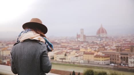 Cheerful-tourist-girl-taking-smartphone-photo-at-amazing-cityscape-panorama-of-autumn-Florence,-Italy,-walking-away.