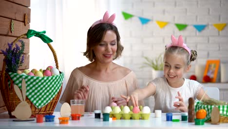 Beautiful-mother-and-daughter-packing-dyed-Easter-eggs-into-box-high-fiving