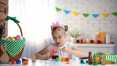 Small-girl-practicing-in-eggs-coloring,-hostess-preparing-for-Easter,-traditions