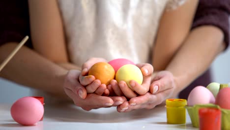 Daughter-and-mother-hands-holding-colorful-eggs-together,-Easter-holiday,-art