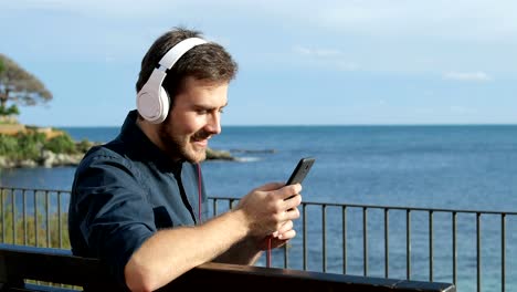 Happy-man-listening-to-music-sitting-on-a-bench