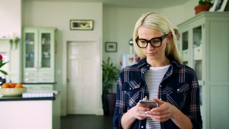 Atractiva-mujer-rubia-mensajes-en-el-teléfono-inteligente-en-oficina-en-casa