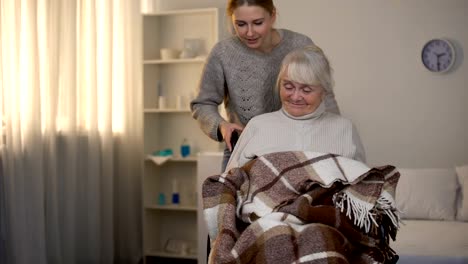 Mujer-voluntaria-cubriendo-suavemente-con-cuadros-vieja-discapacitada,-hogar-de-ancianos