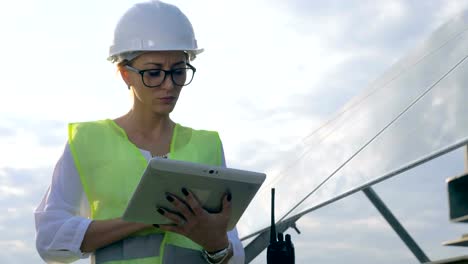 Female-engineer-works-with-a-tablet-near-solar-panels,-close-up.