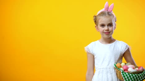 Happy-Easter-text,-cute-child-with-eggs-basket-in-bunny-ears-showing-thumbs-up