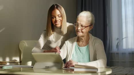 Grandmother-Learning-Digital-Tablet-with-Help-of-Young-Woman