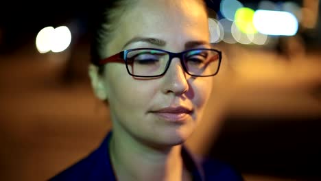 Portrait-of-young-beautiful-caucasian-woman-using-smart-phone-hand-hold-outdoor-in-the-city-night,-smiling,-face-illuminated-screenlight---social-network,-technology,-comunication-concept