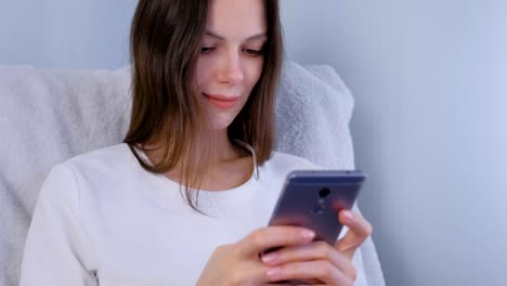 Young-brunette-woman-types-a-message-on-a-mobile-phone.