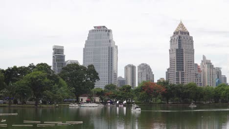 Stadtbild:-Grünes-Laubenbaumbild-und-großer-See-vor-Wolkenkratzern-in-der-Innenstadt.-Gebäude-und-Stadtpark-an-der-Skyline