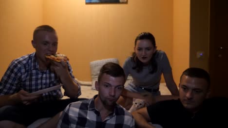 Gruppe-von-Menschen,-die-Comedy-Film-oder-lustige-Social-Media-Video-auf-dem-Laptop-zu-Hause.-Glücklicher-Mann-essen-eine-Scheibe-Pizza,-während-Sie-Online-TV-Show-auf-dem-Computer.-Junge-Mädchen-streicheln-Katze-im-Bett-sitzen.