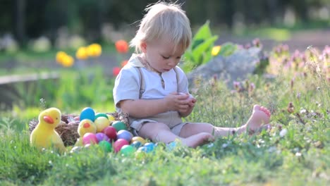 Sweet-toddler-boy-with-bunny-ears,-egg-hunting-for-Easter,-child-and-Easter-day-traditions.-Kids-and-holidays