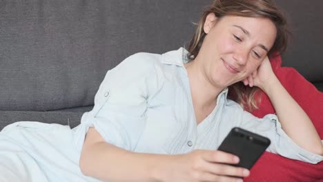 Smiling-girl-holding-smartphone-in-hand-at-home