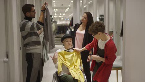 Woman-in-Wheelchair-Shopping-for-Clothes-with-Help-of-Friends