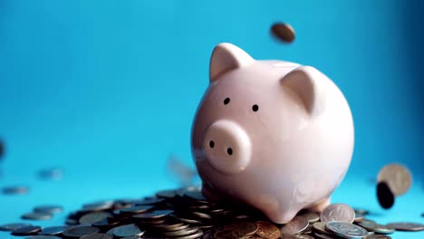 Man-putting-coins-in-piggy-bank-of-pig-shape-in-pile-of-coins,-hand-closeup