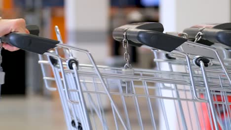 a-woman-holds-a-coin-in-her-hand-to-rent-a-shopping-cart