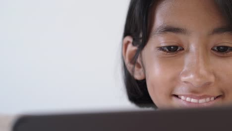 Close-up-of-Asian-girl-watching-video-via-online-media-On-tablet-for-entertainment-And-smiling-happily-while-sitting-on-the-sofa