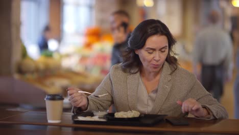 Frau-mit-Telefon-und-Mittagessen-am-Tisch-in-Lebensmittelmarkt