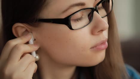 Closeup-woman-puts-on-wireless-earbuds